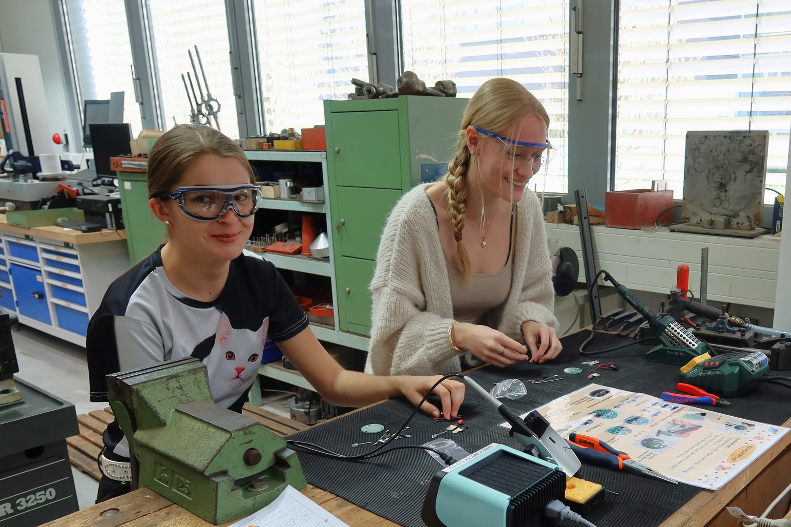 two young girls soldering at a workshop table
